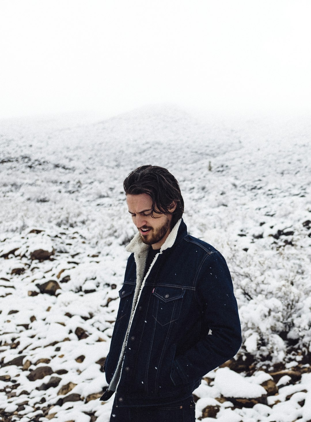 man in black jacket walking on snow