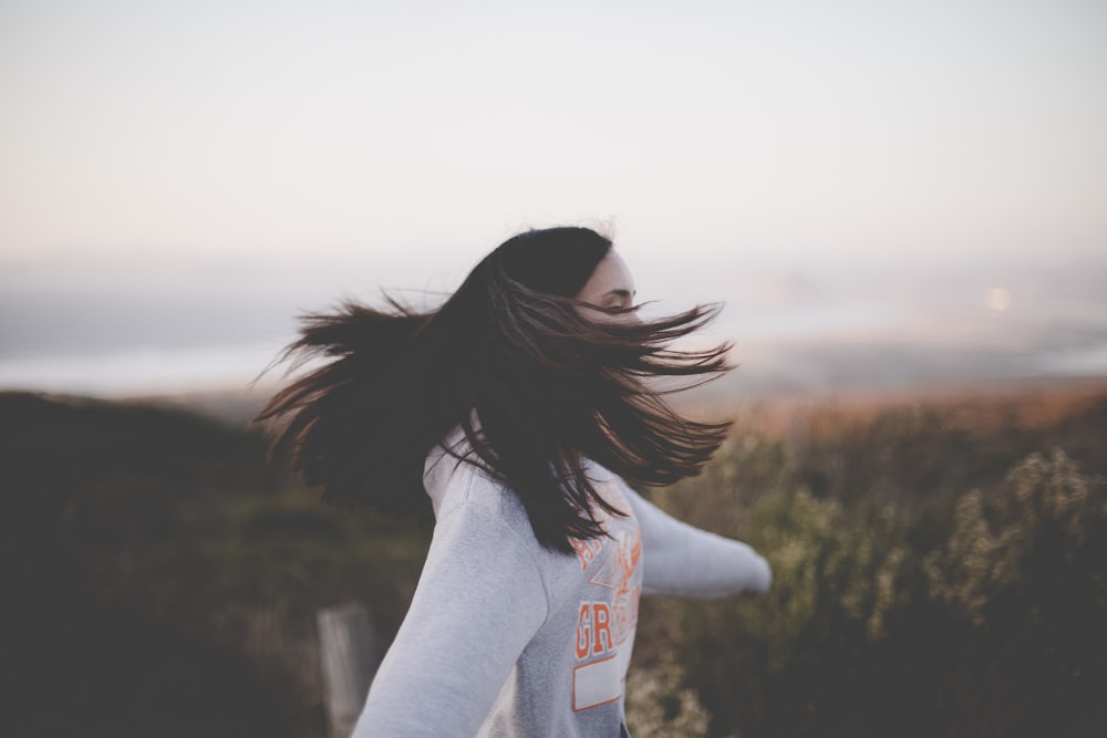 woman flips her hair while jumping on the mountain