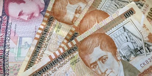 A collection of Honduran banknotes featuring portraits of historical figures and intricate architectural designs. The notes display a variety of textures and patterns in warm colors.