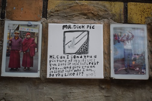 The image shows a wall with three framed pieces. On the left, there is a photo of two people dressed in red clothing standing outside a shop, with the word 'ZIG ZAG' visible in the background. The center piece is a tile with hand-drawn art and text, humorously labeled 'MR. Dick Pic' with a sketch and a playful message asking to send a picture. On the right, a photo depicts a person posing in an indoor setting, dressed casually, with various items visible around the room.