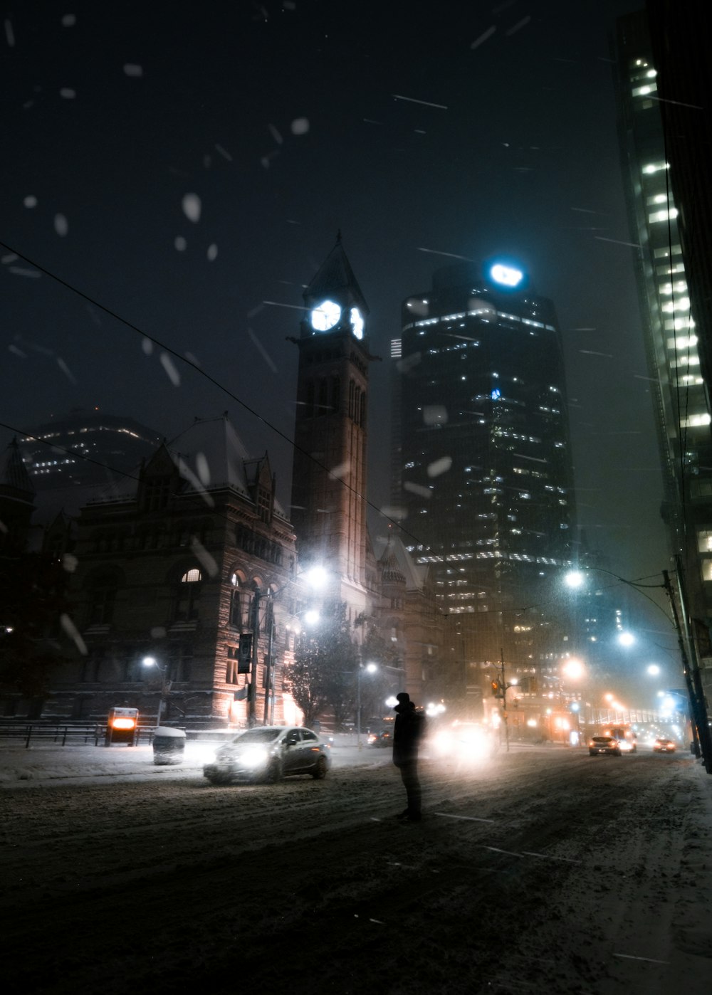 a person standing on a snowy street at night