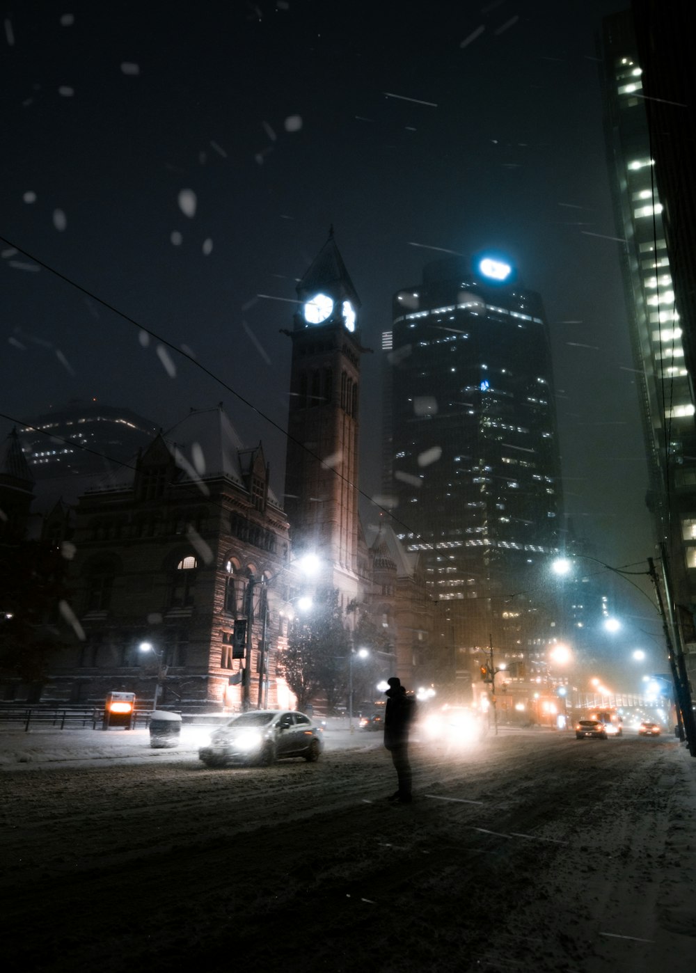 Una persona parada en una calle nevada por la noche