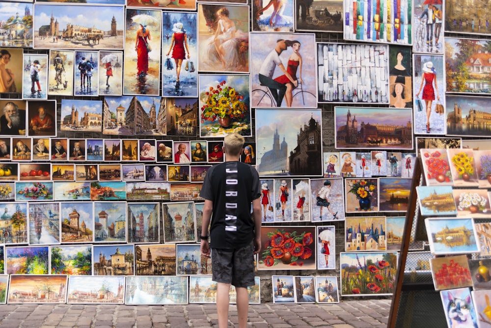 photography of standing man starring on assorted photos during daytime