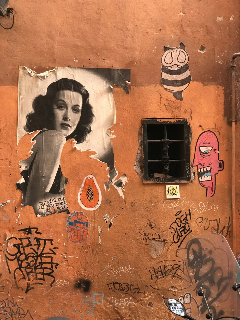 a wall covered in graffiti with a picture of a woman