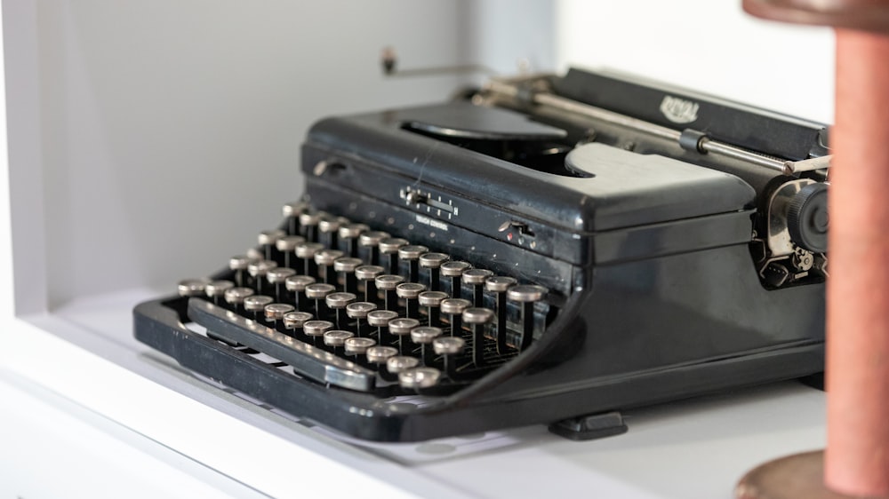 black typewriter beside wall
