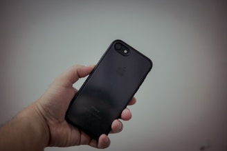 A close-up of hands holding a sleek smartphone with the UK flag subtly visible in the background.
