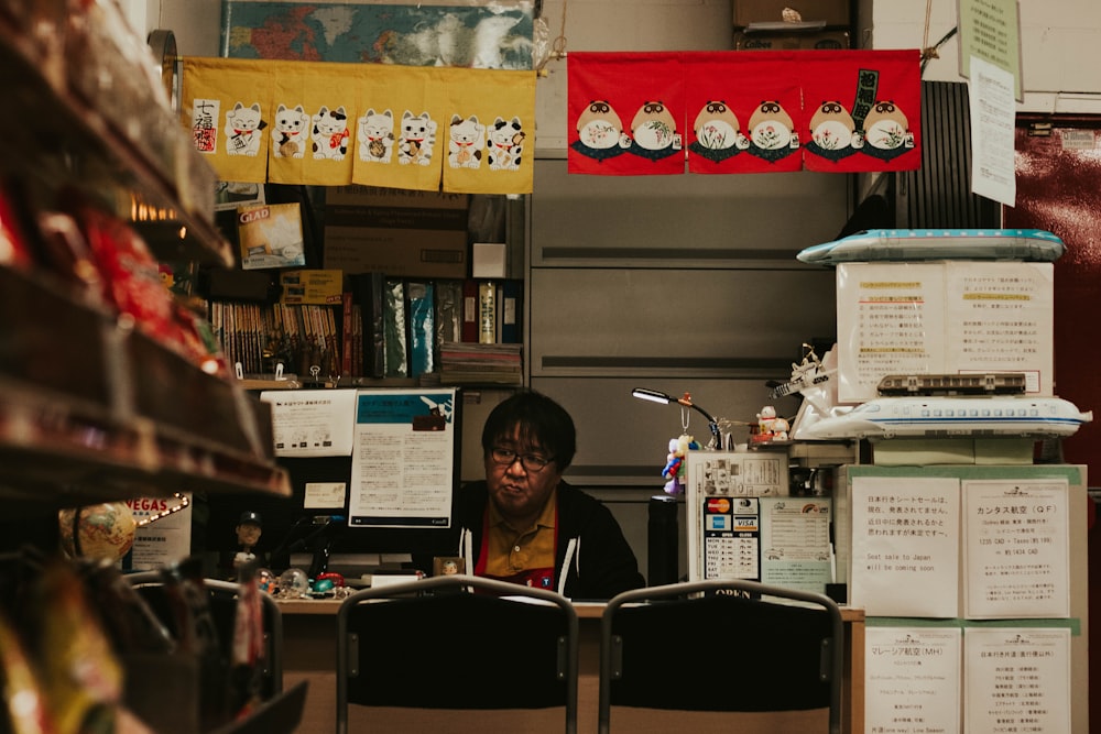 person in black top sitting beside table and shelf