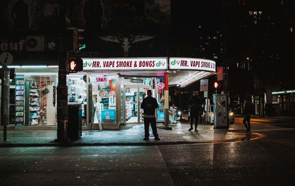 people near store beside road at night