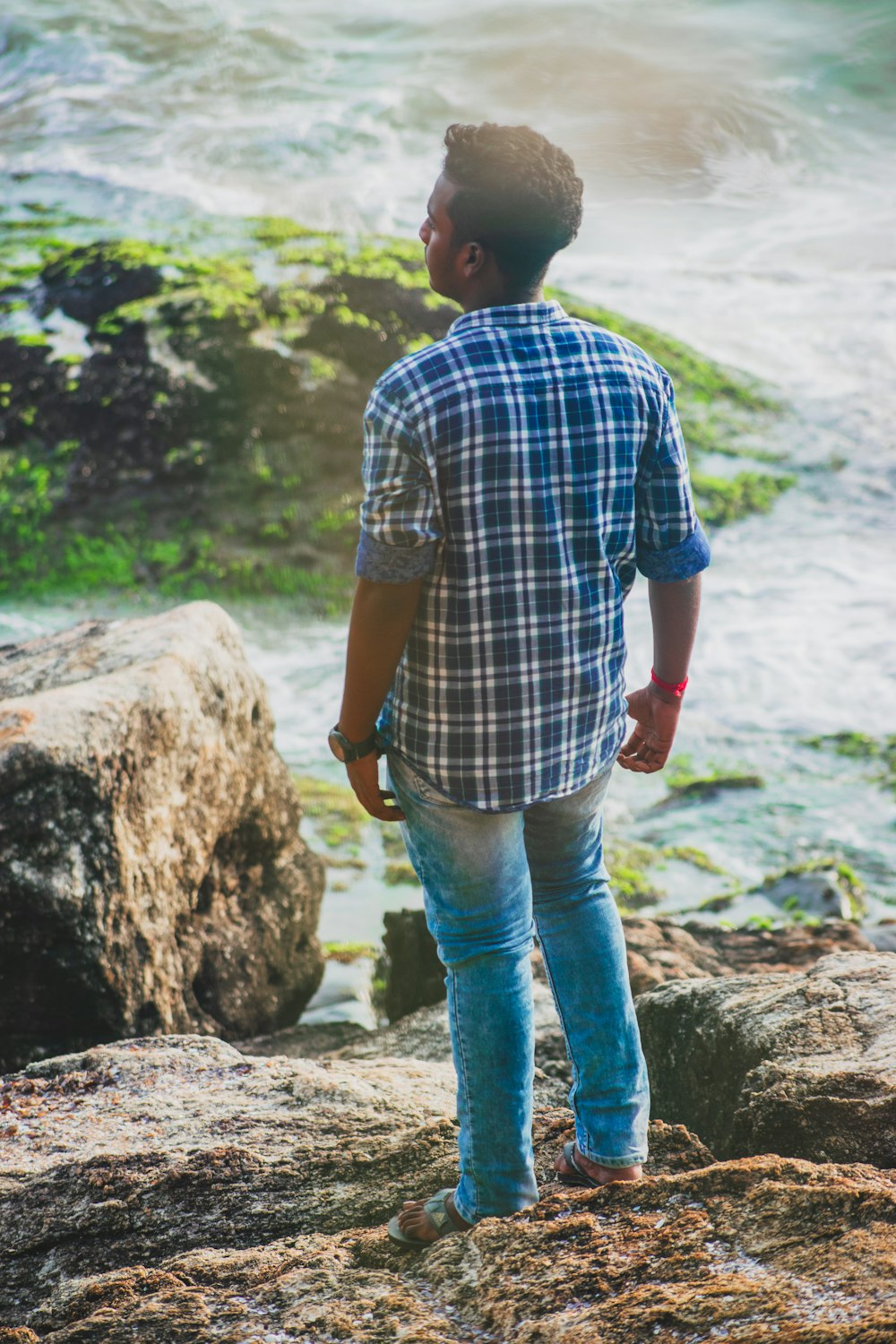 man standing on rock near river