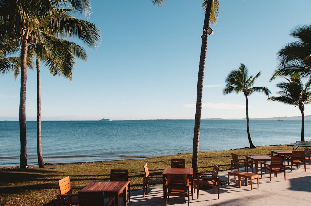 brown wooden tables and chairs near seashore