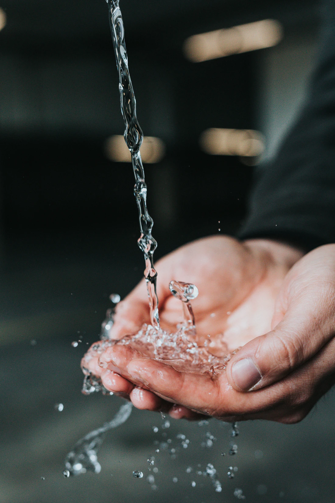 Hände unter fließendem Wasser als Symbol für Ausscheidung und körperliche Erholung