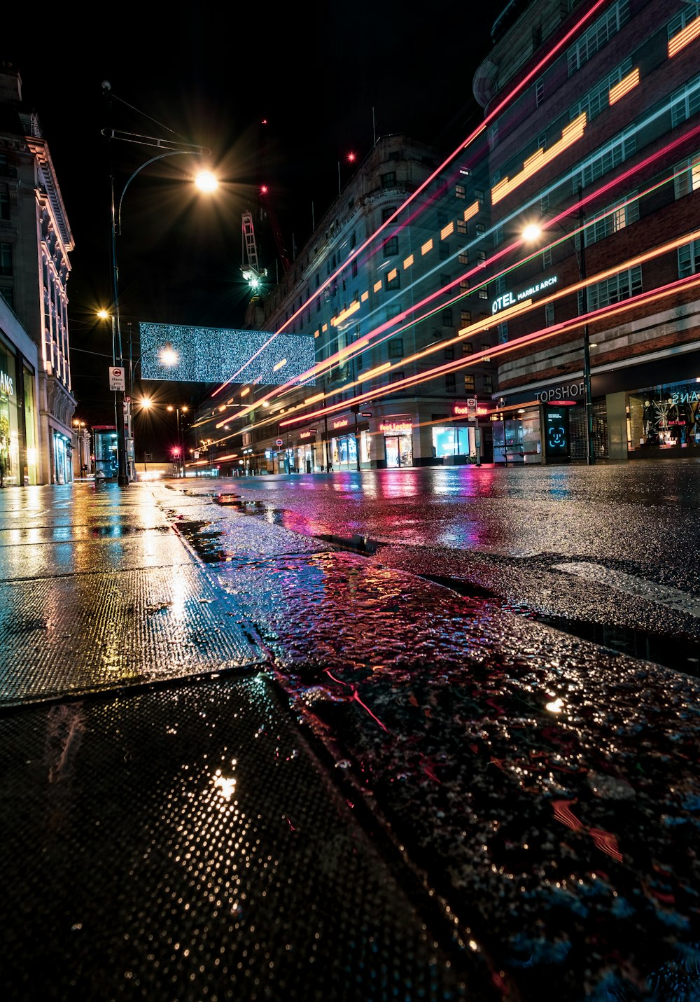 a wet city street at night with buildings lit up