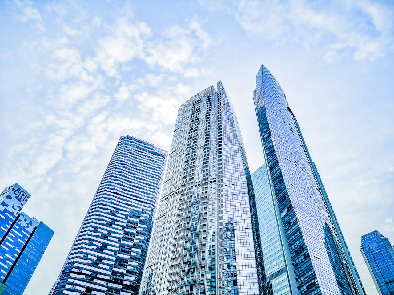 Looking up at a glass office tower in Singapore against a blue sky
