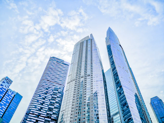 Looking up at a glass office tower in Singapore against a blue sky