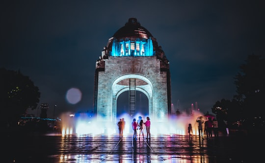 five person standing behind arch tower in Plaza de la República Mexico
