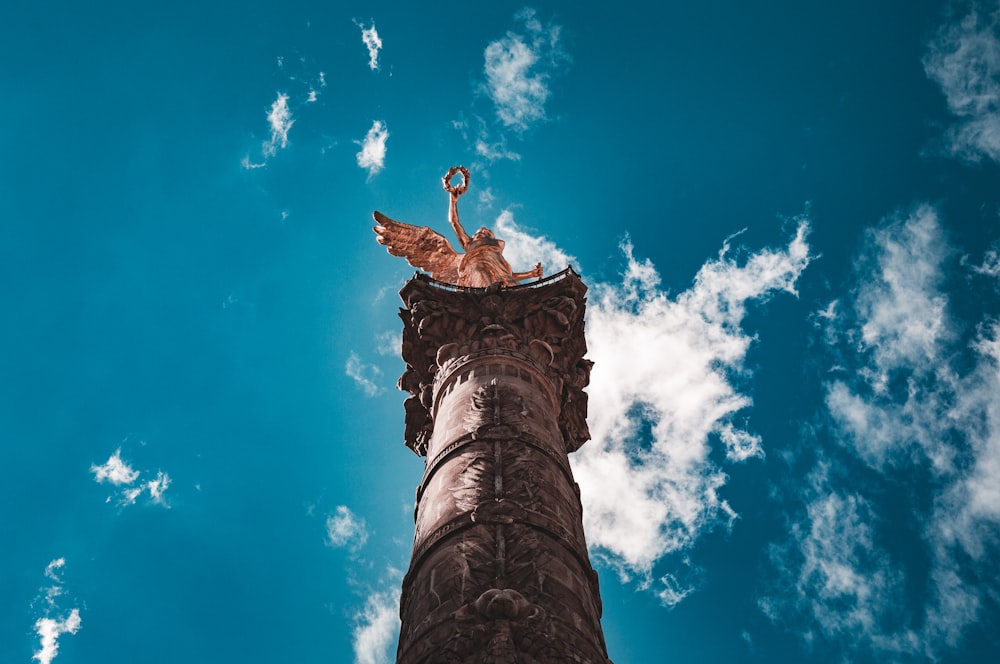 una torre alta con una estatua en la parte superior