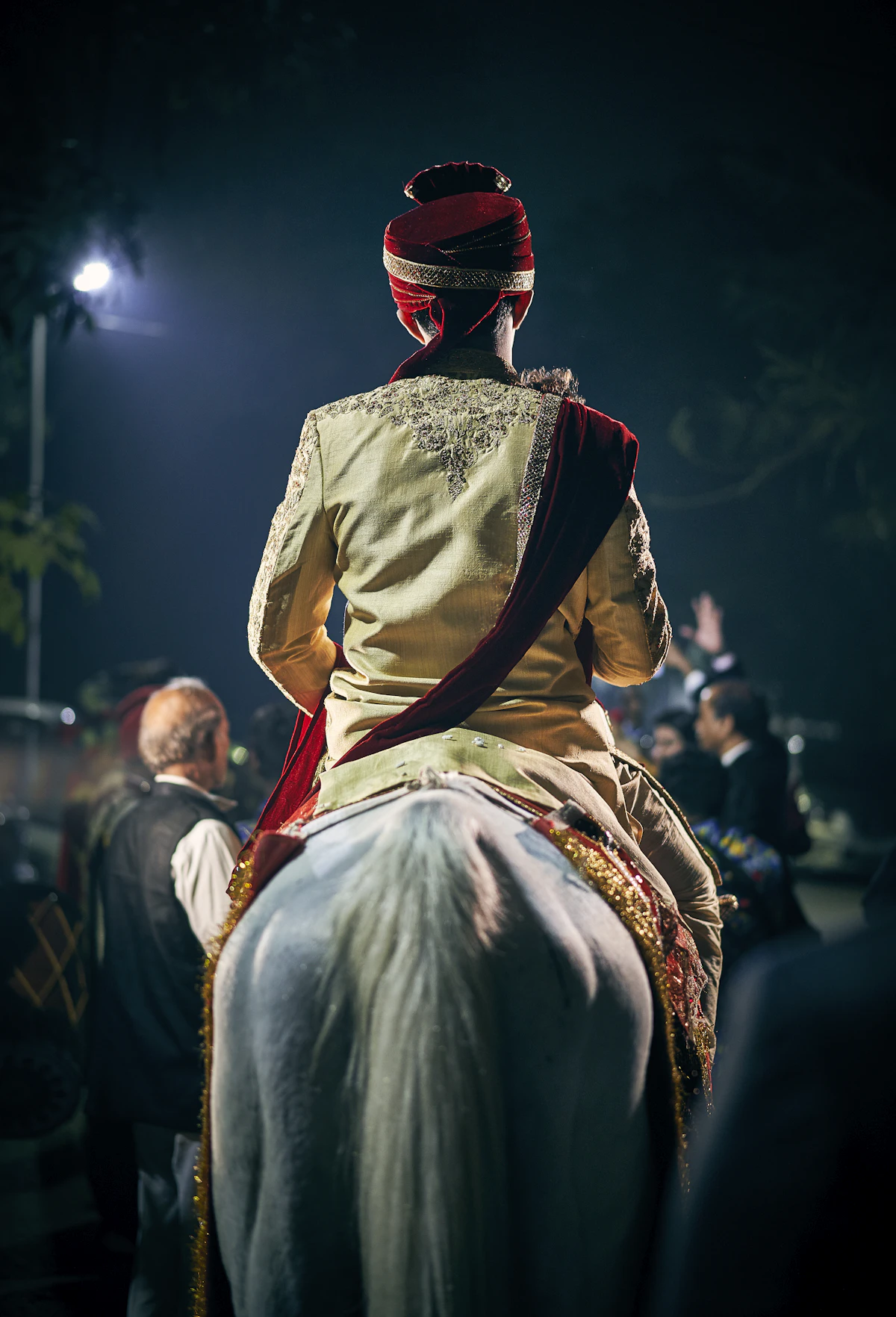 A groom on a horse surrounded by people at night