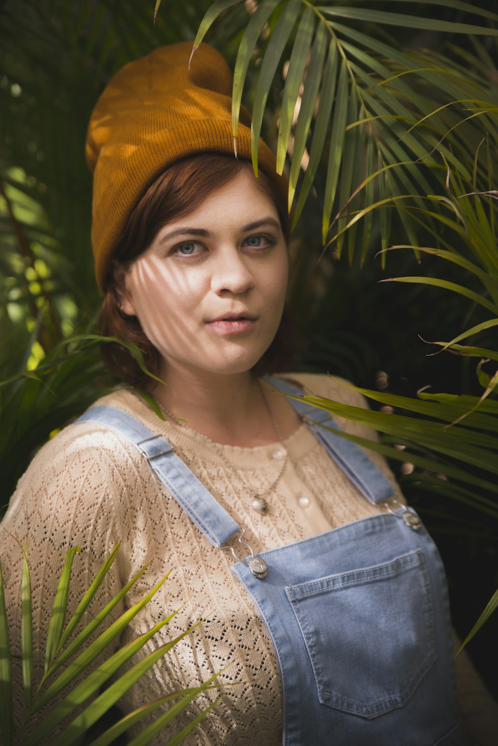 woman in brown and blue top beside palm plants