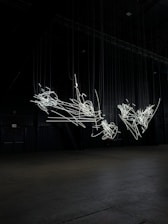 A stark black and neon green brutalist grid installation with dynamic light patterns pulsing in a dark club space.