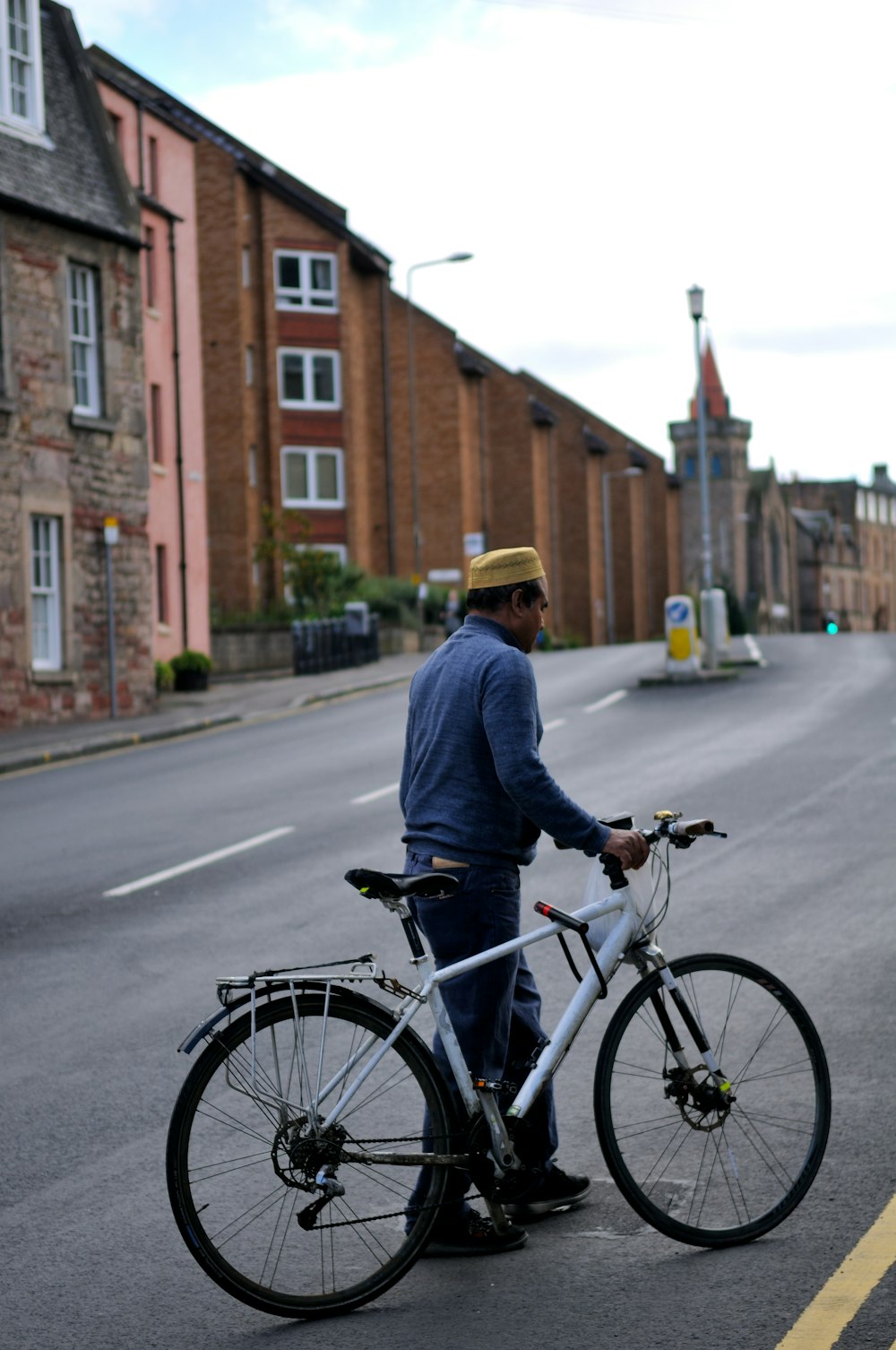 man in blue dress shirt holding white hardtail bike