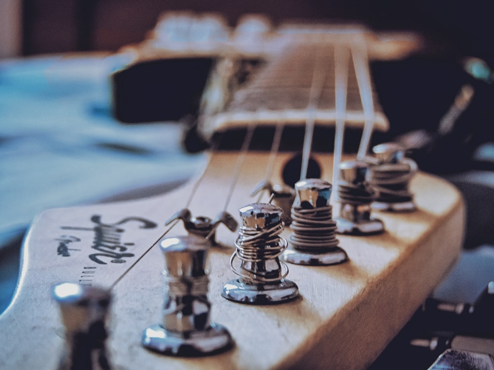 a close up of a guitar neck with strings and knobs