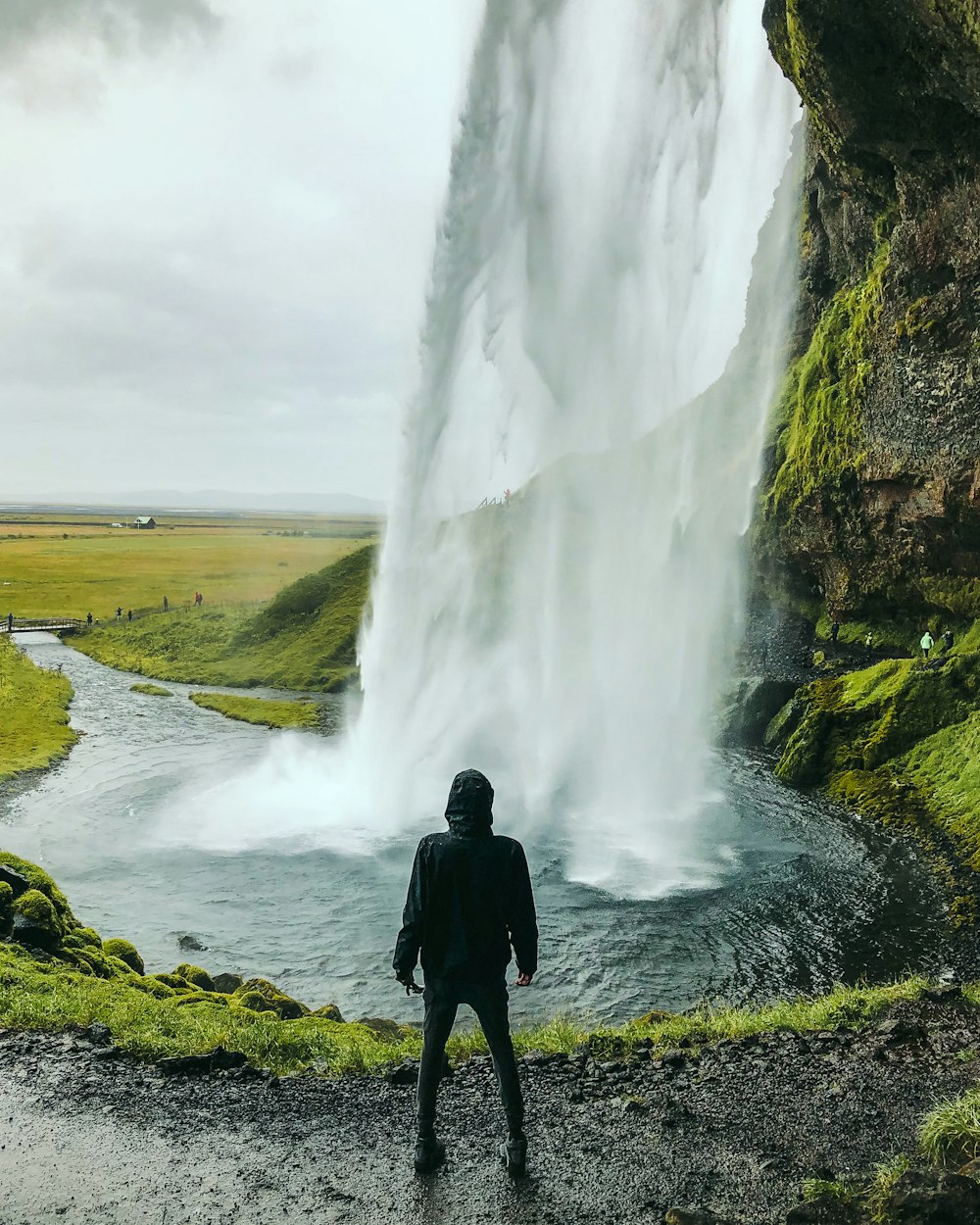 Mann steht vor Wasserfall