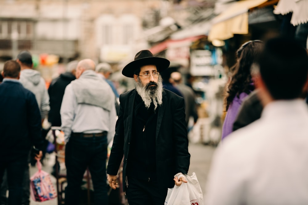 uomo che indossa cappotto nero e cappello