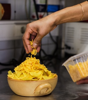 Close-up of a hand sprinkling cheese over a hot, golden coxinha.