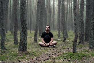 man in black shirt sitting in woods