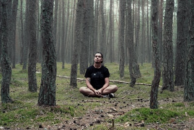 man in black shirt sitting in woods