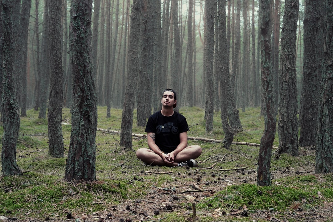 man in black shirt sitting in woods