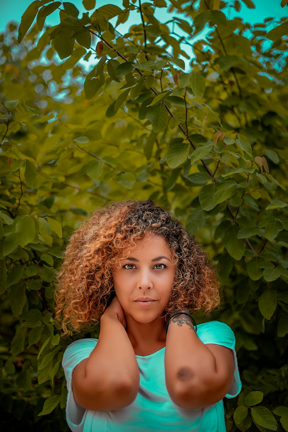 femme en chemise turquoise à côté de la plante