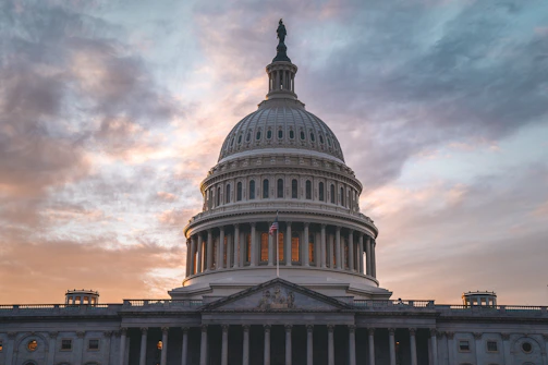 The United States Capitol dome glowing warmly at sunset.