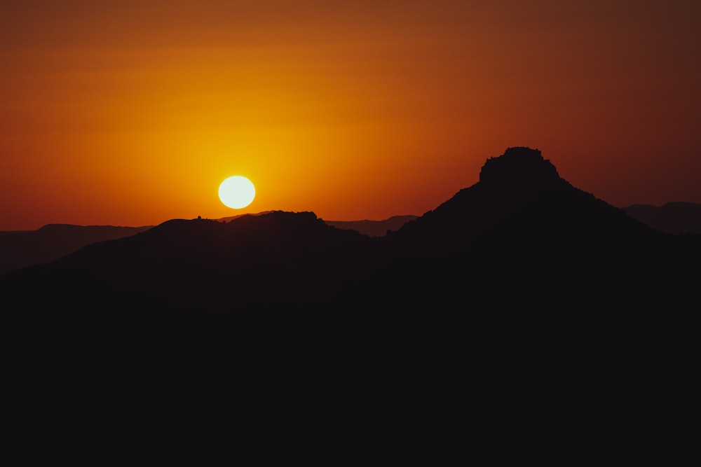 the sun is setting over a mountain range