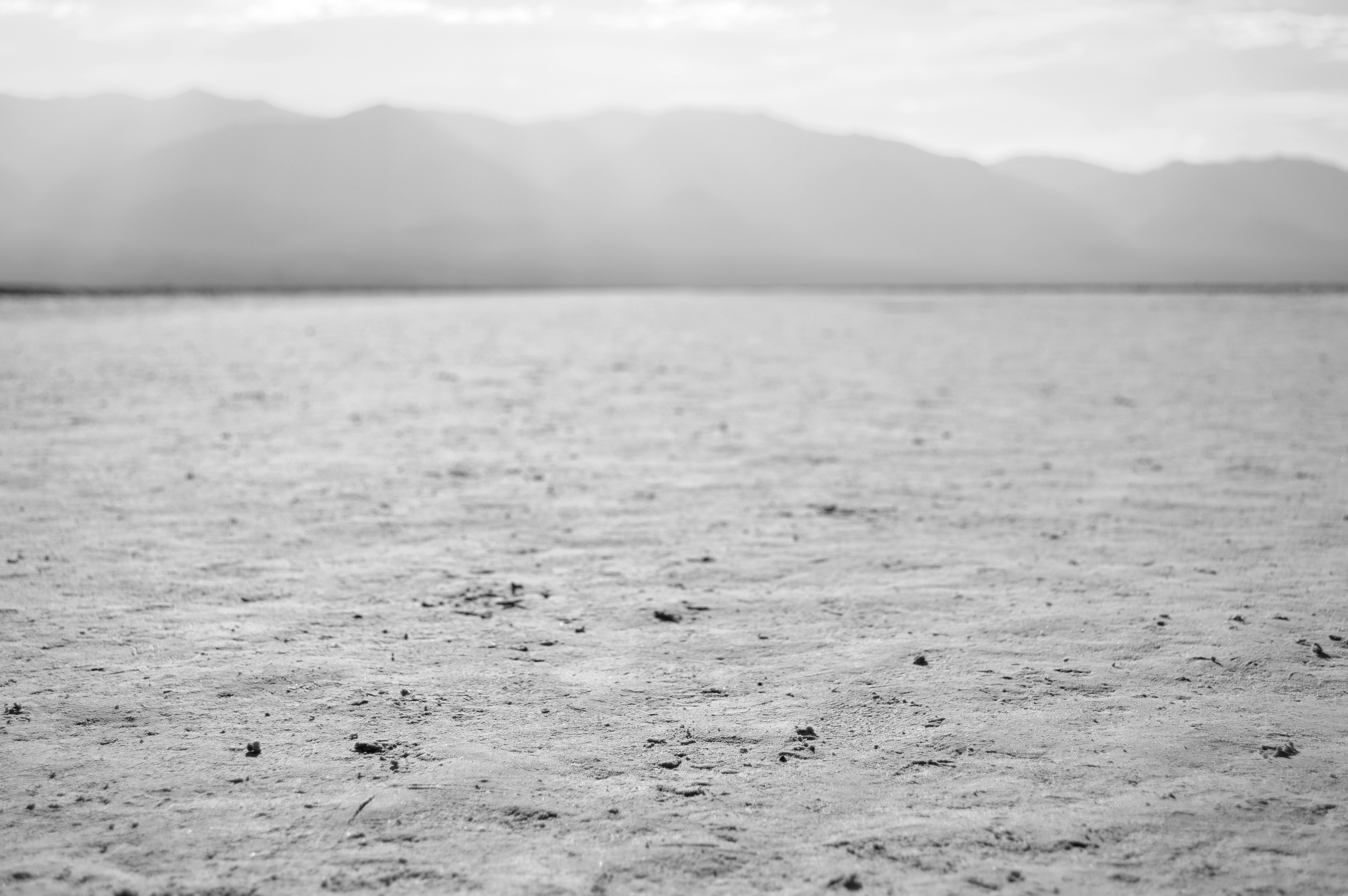 Vast desert highway vanishing into shimmering heat haze, cracked dry earth flanking both sides