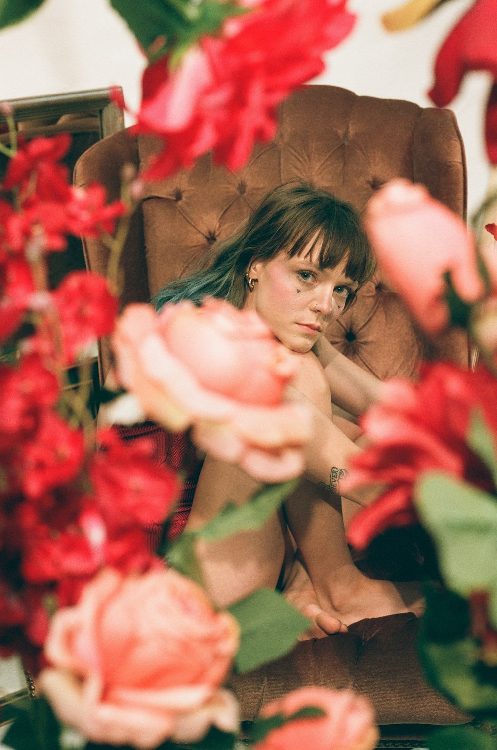 selective focus photo of woman sitting on tufted brown sofa chair with flowers