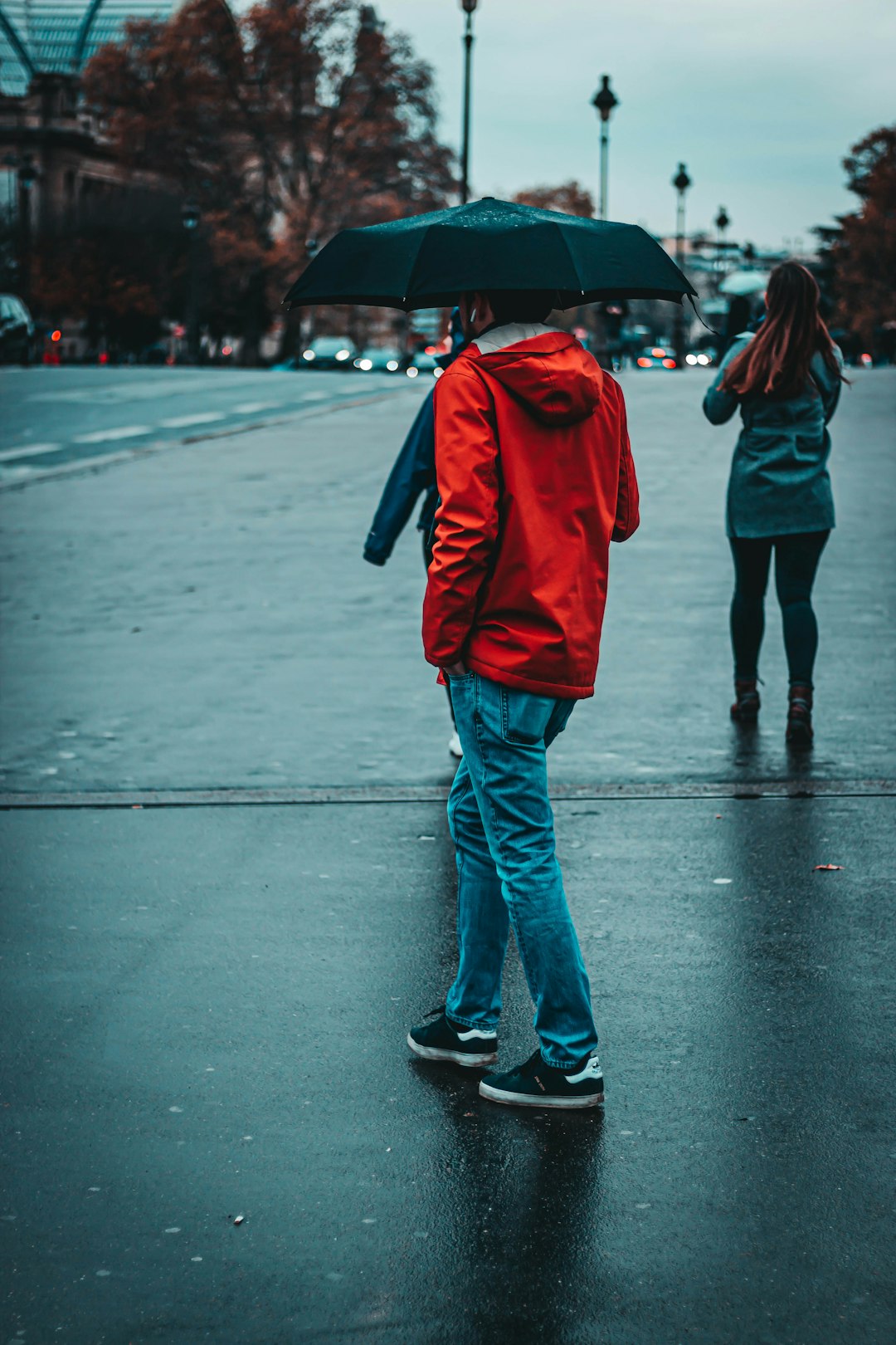 person in red hoodie holding black umbrella