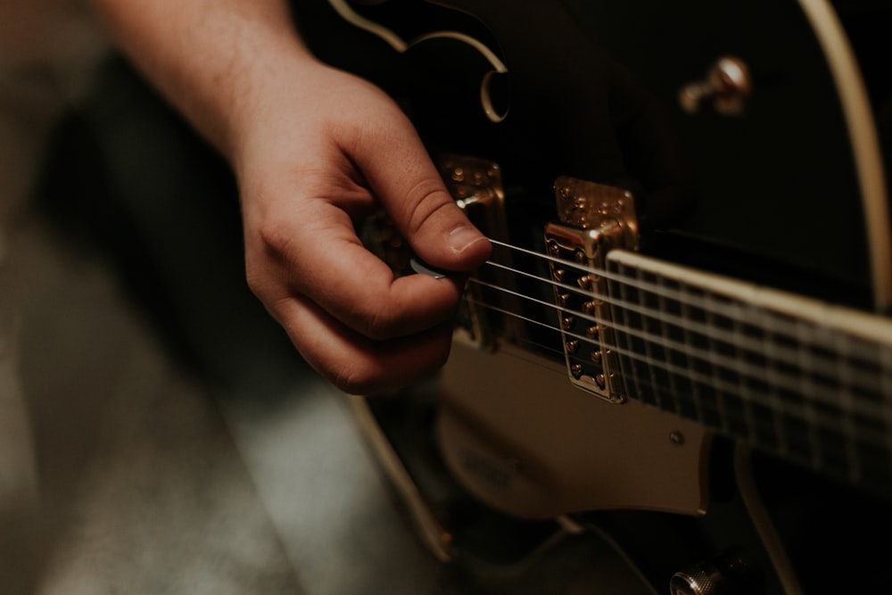 Persona sosteniendo una guitarra negra