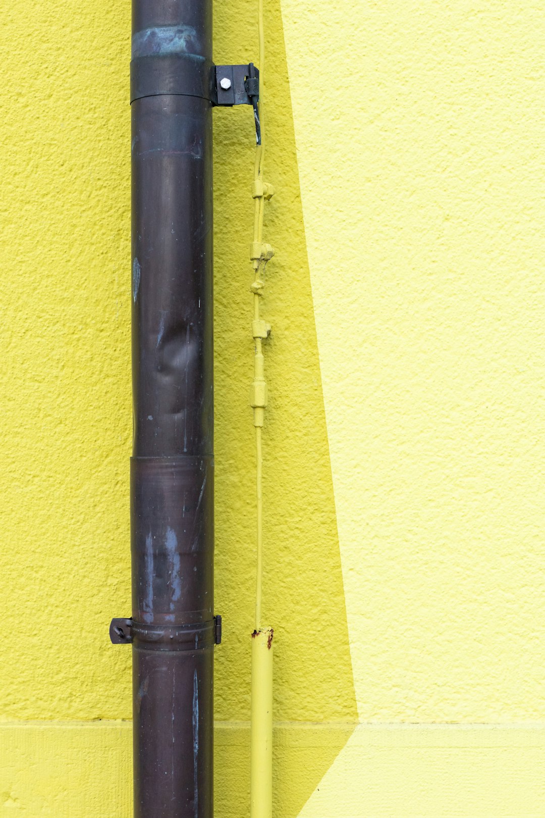 black metal pipe on yellow painted wall