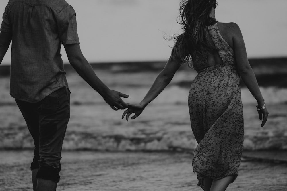 man and woman walking on beach