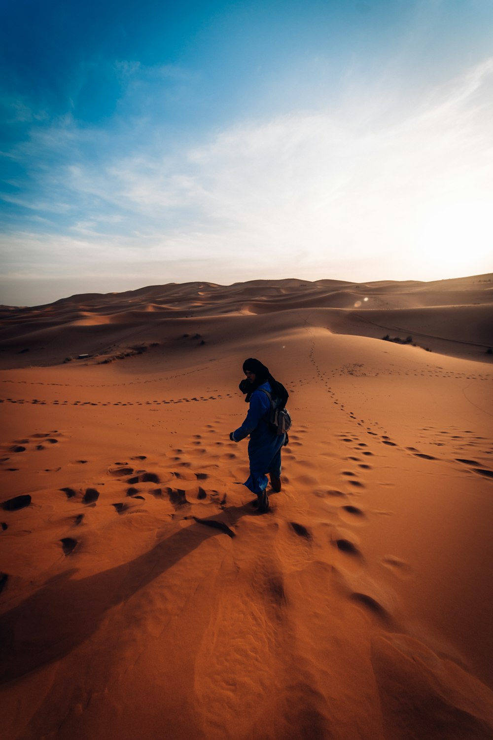 person walking on sand dunes during daytime
