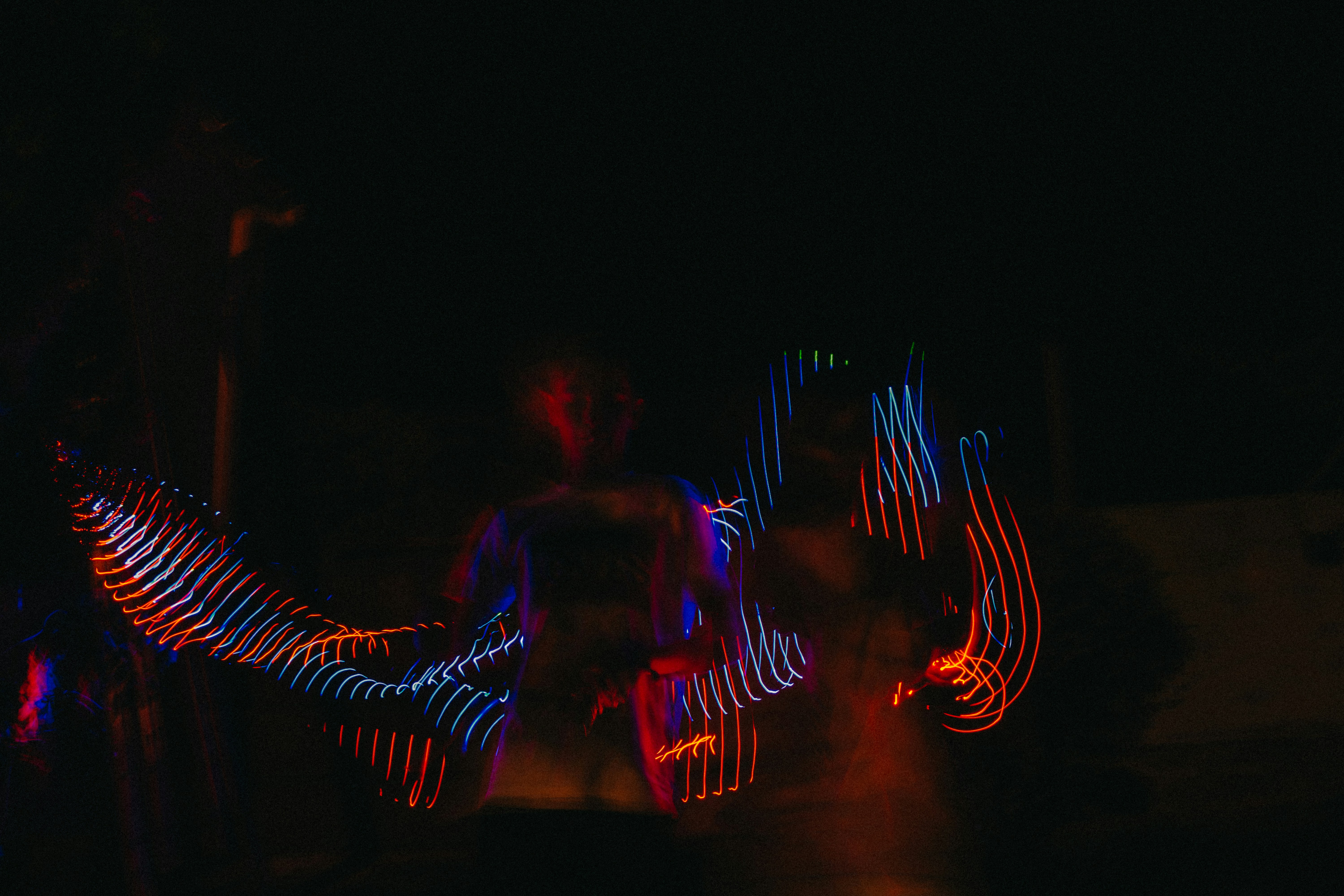 a man standing in the dark with his arms spread out