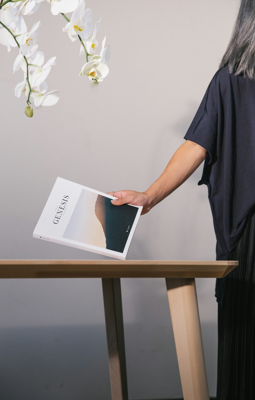 Frau steht neben dem Tisch und hält das Buch Genesis in der Hand