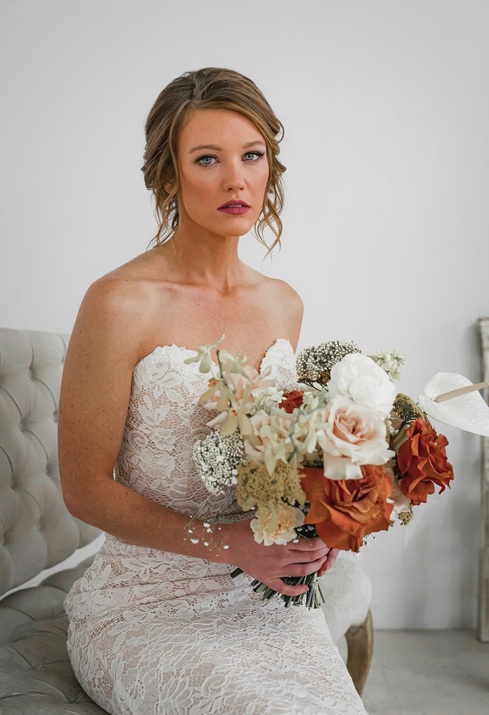 woman in white off-shoulder wedding dress holding bouquet of flowers