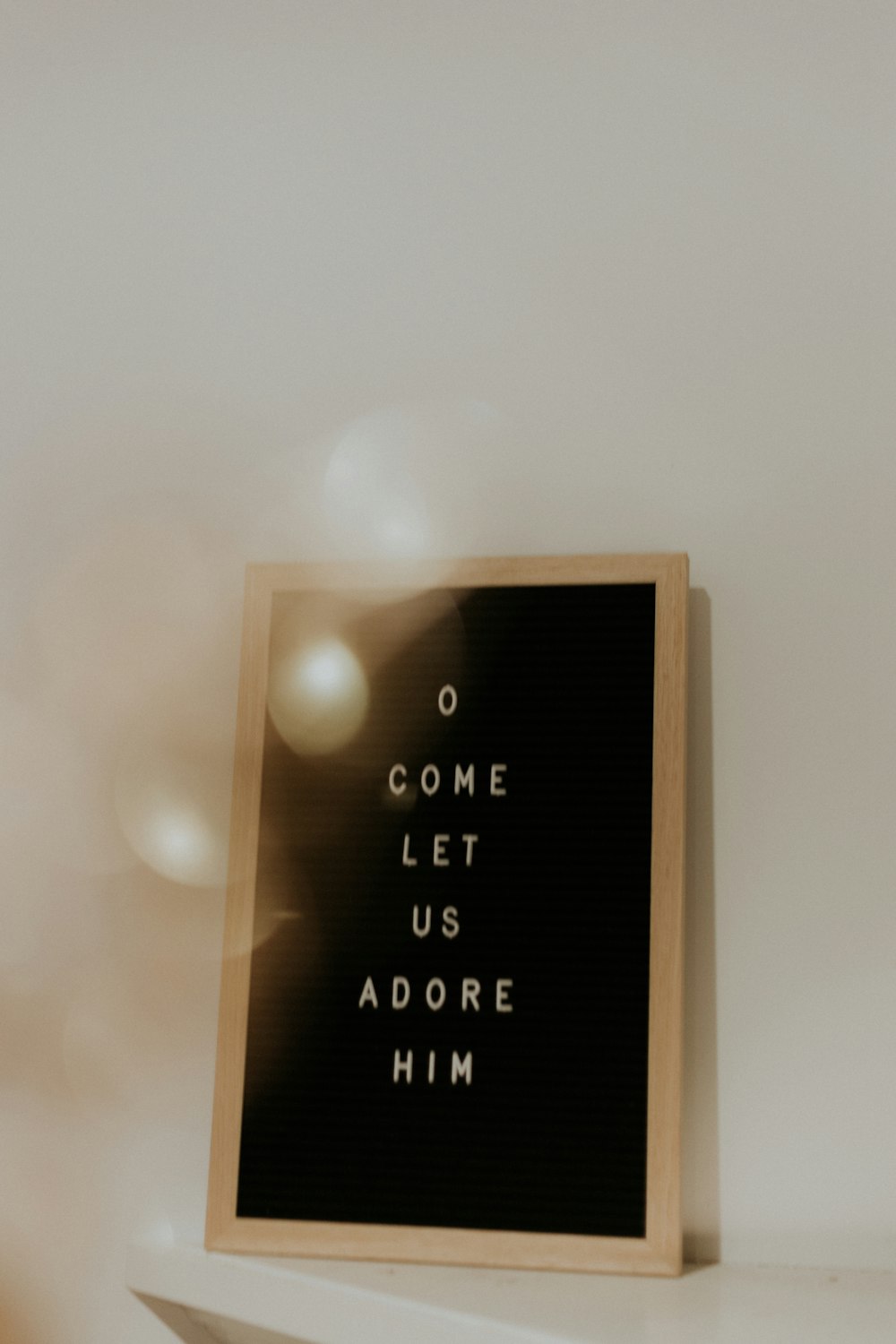 shallow focus photo of come let us adore him quoteboard with brown wooden frame