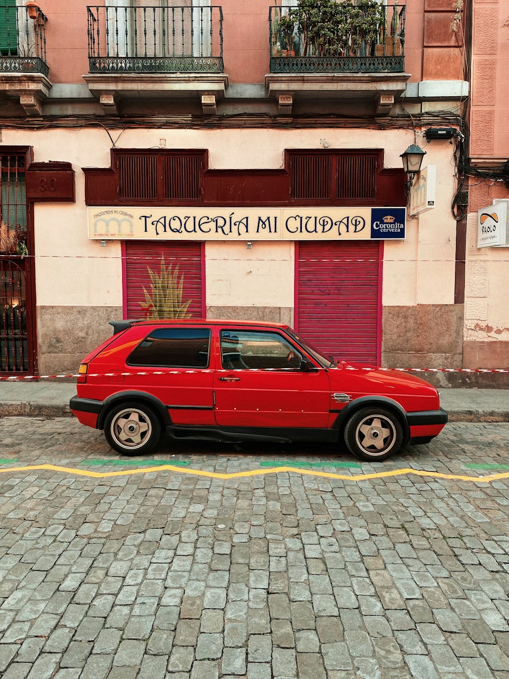 red 3-door hatchback parked in front of Taqueria Mi Ciudad building