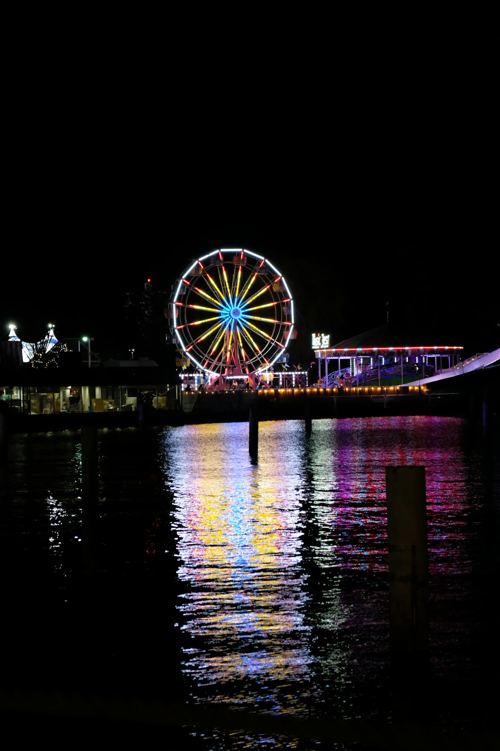 lighted Ferris wheel reflecting on body of water
