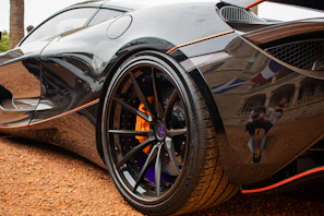 Wide angle of a fully detailed car parked on a black floor, highlighting the depth of the shine