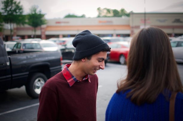 A friendly Line Design crew member chatting with a smiling client beside a striped parking lot.