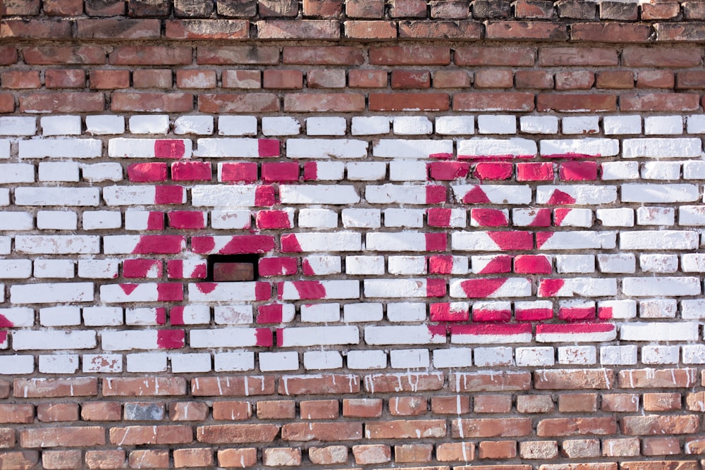 a brick wall with a red and white sign painted on it